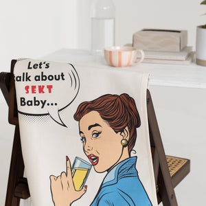 Geschirrtuch „Let’s talk about Sekt Baby“ als stilvolle Küchendeko mit humorvollem Sekt Statement über eine Stuhllehne gehängt