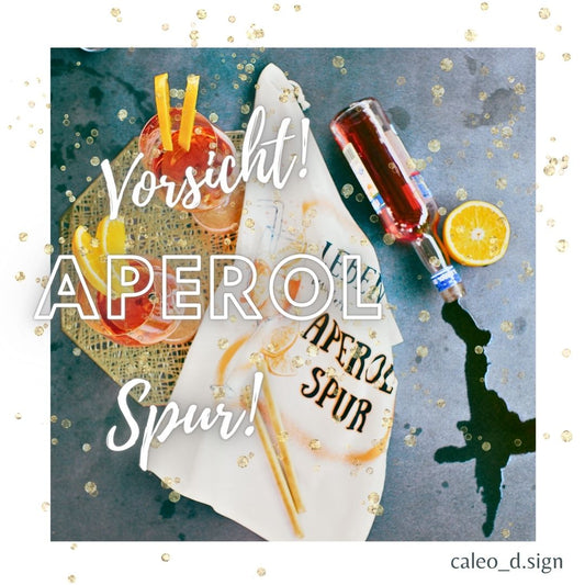 Modernes Geschirrtuch mit lustigem Aperol Spruch und Cocktail Motiv, nachhaltiges Küchenhandtuch mit orangenen Akzenten und Öse zum Aufhängen.