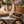 Bambus-Weinbox „In dubio Prosecco“ mit Prosecco-Gläsern und Weinaccessoires auf gemütlichem Gartentisch bei sommerlicher Abendstimmung mit Lichterketten und Freunden im Hintergrund