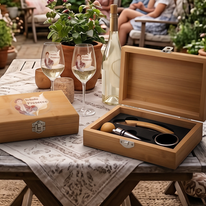 Bambus-Weinbox „In dubio Prosecco“ mit Prosecco-Gläsern und Weinaccessoires auf gemütlichem Gartentisch bei sommerlicher Abendstimmung mit Lichterketten und Freunden im Hintergrund